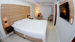 Una habitación de hotel moderna con una cama grande, mesitas de noche, un escritorio y un televisor.