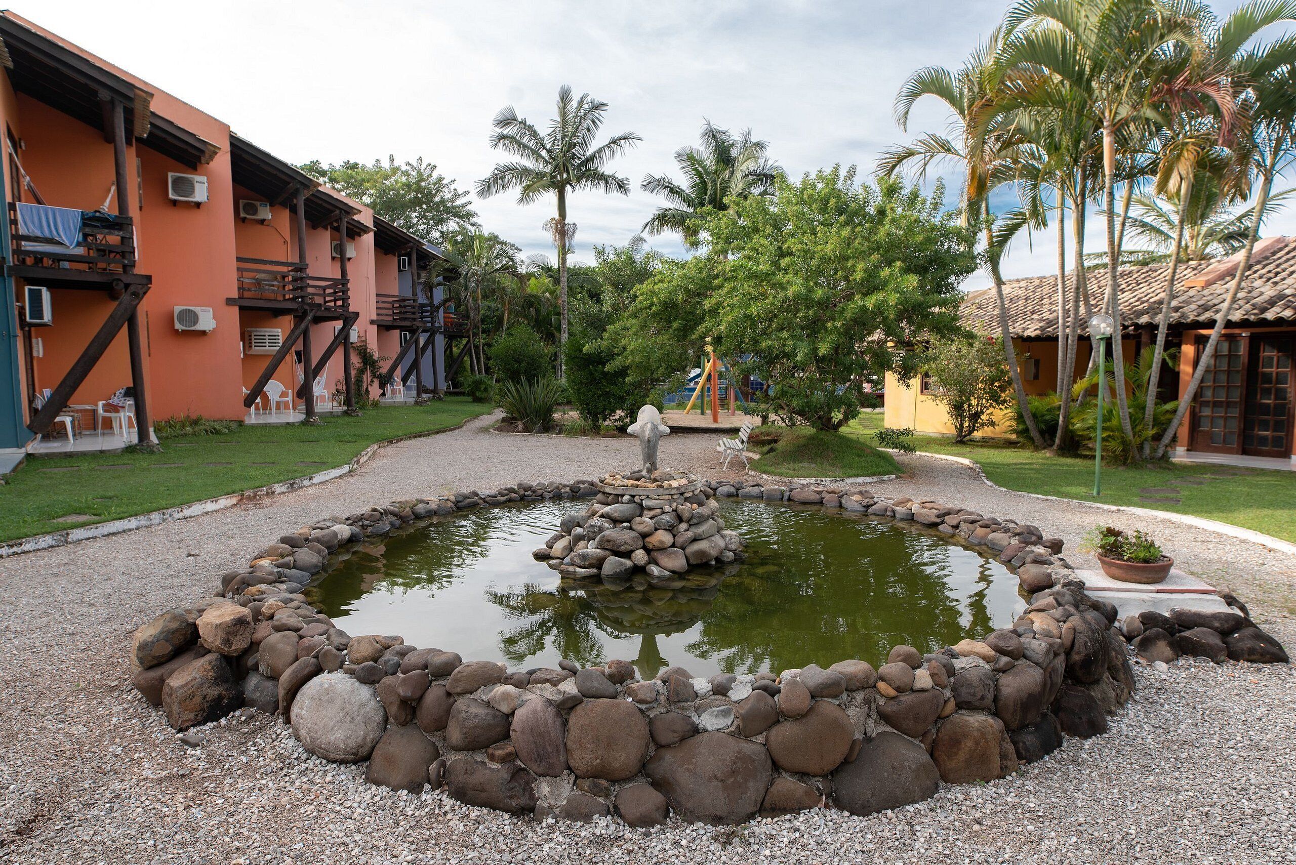 A courtyard with a circular pond, stone border, and surrounding buildings.