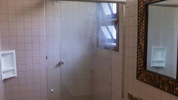 A bathroom with a glass-enclosed shower, a sink with a granite countertop, and a mirror with a decorative frame.