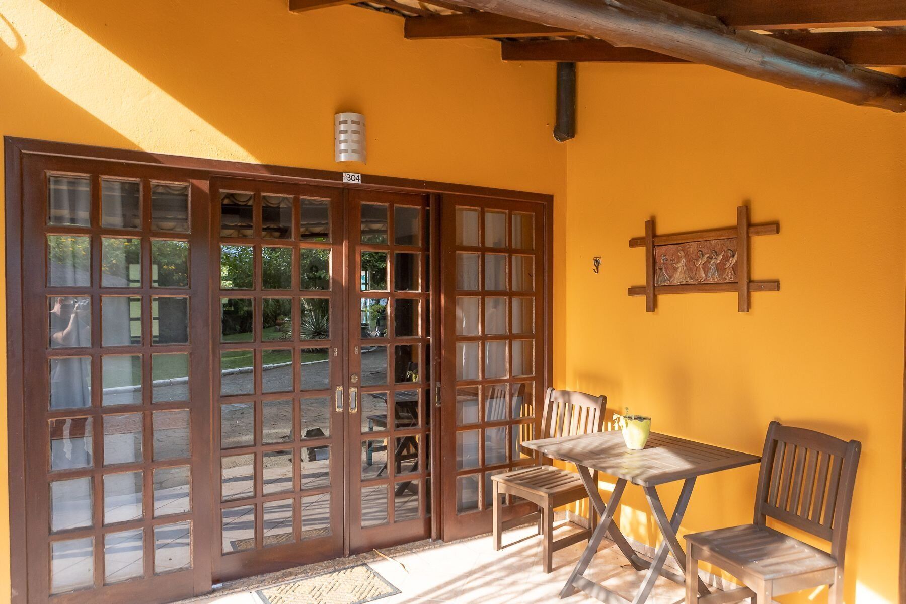 A room with a large wooden door, a small table with chairs, and a wall-mounted picture.