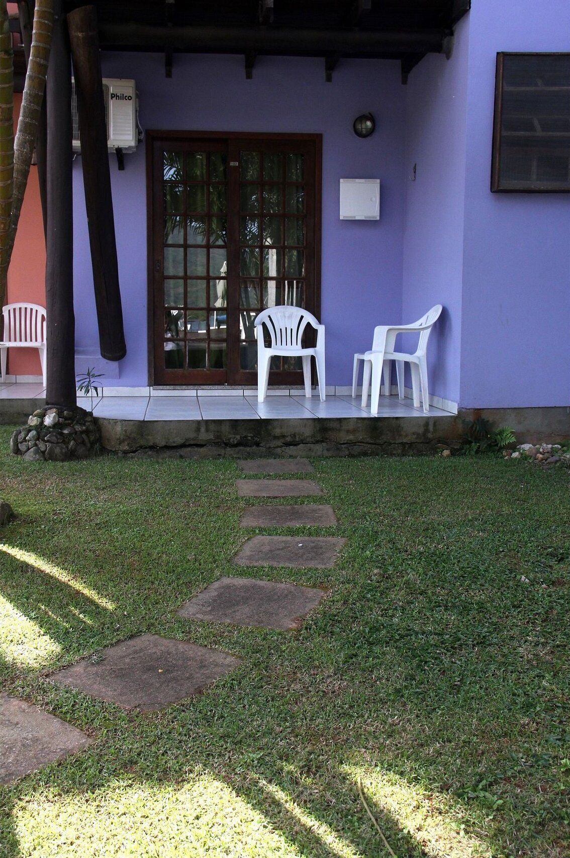 A building with a purple exterior, a glass door, and two white plastic chairs on the porch.