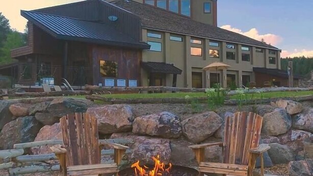 Una casa moderna con un pozo de fuego de piedra y sillas de madera.