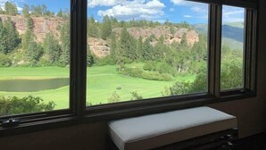 Una habitación con un gran ventanal con vistas a un campo de golf y un acantilado rocoso.
