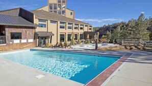 Un hotel moderno con piscina, un telón de fondo montañoso y cielo despejado.