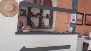 A modern interior with a reception desk, a staircase, and a wall with shelves. - Vivenda Viviani (Praia)