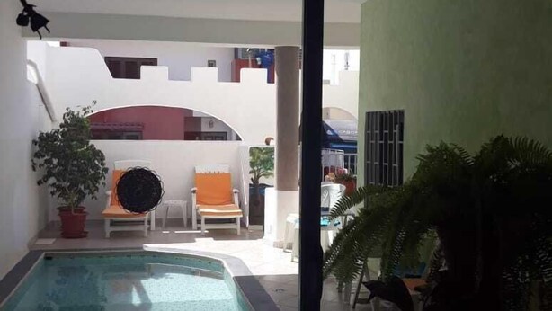 A pool area with a clear view of the pool, a chair, and a potted plant. - Vivenda Viviani (Praia)