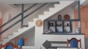 A staircase leading to a second floor with a dining area below. - Vivenda Viviani (Praia)