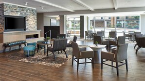 A spacious indoor area with a fireplace, seating arrangements, and large windows offering views of the outdoors. - Residence Inn by Marriott Cleveland University Circle/Medical Center (Cleveland)