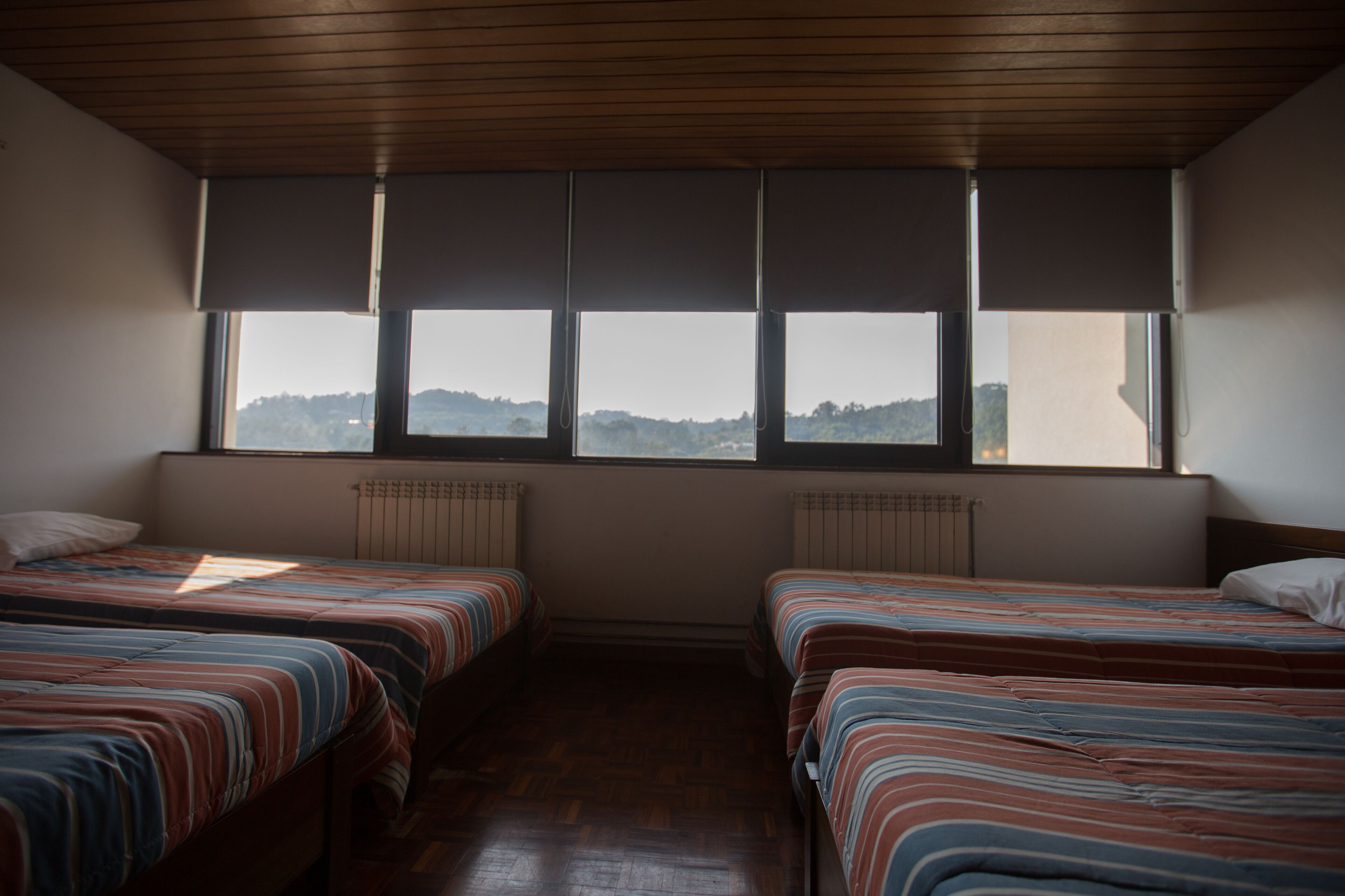 A room with two beds, a large window, and a radiator.