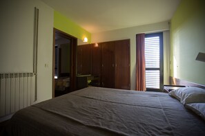 A bedroom with a bed, a wardrobe, a radiator, and a window with curtains. - HI Sao Pedro do Sul Pousada de Juventude - Hostel (Sao Pedro do Sul)