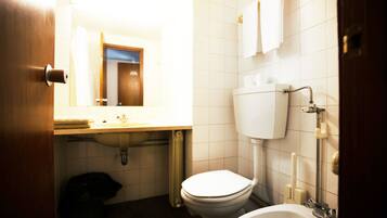 Une petite salle de bain avec des toilettes, un lavabo et une baignoire.