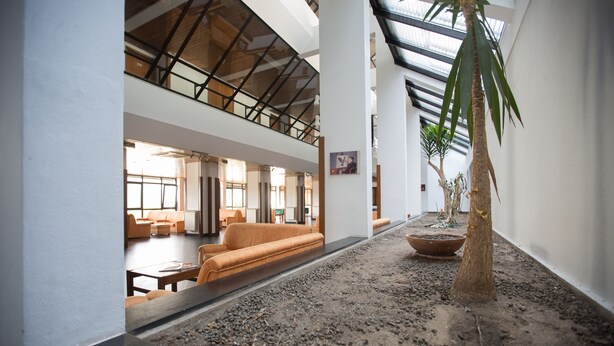A spacious lobby with a high ceiling, a central seating area with orange sofas, and a potted plant. - HI Sao Pedro do Sul Pousada de Juventude - Hostel (Sao Pedro do Sul)