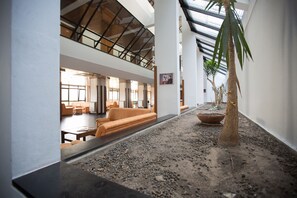 A spacious lobby with a high ceiling, a central seating area with orange sofas, and a potted plant. - HI Sao Pedro do Sul Pousada de Juventude - Hostel (Sao Pedro do Sul)