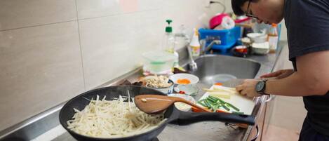 Una cocina con estufa, sartén y diversos utensilios de cocina.