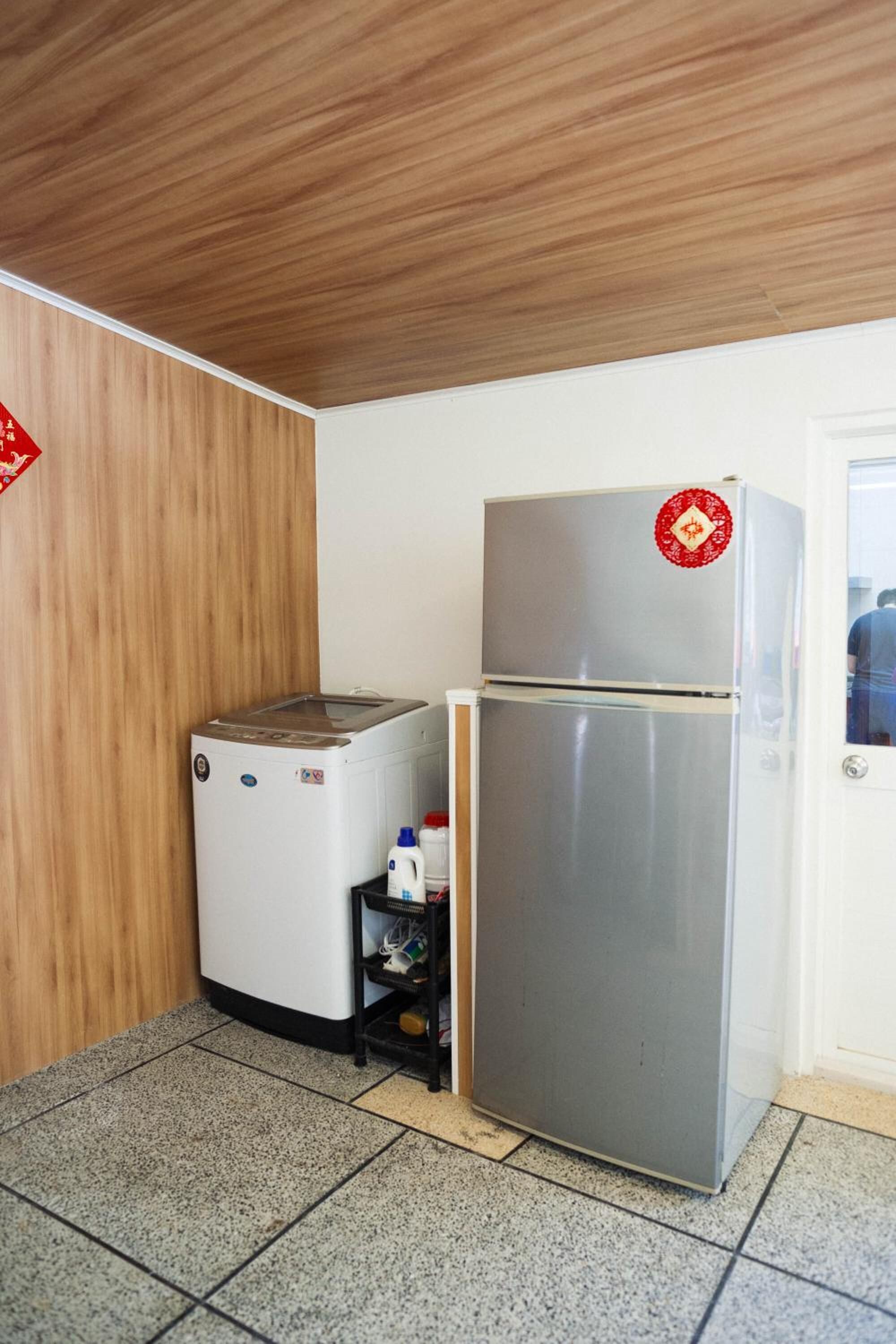 Una cocina compacta con un refrigerador de acero inoxidable, una lavadora pequeña y un microondas.