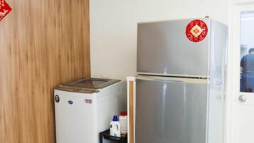 Una cocina compacta con un refrigerador de acero inoxidable, una lavadora pequeña y un microondas.