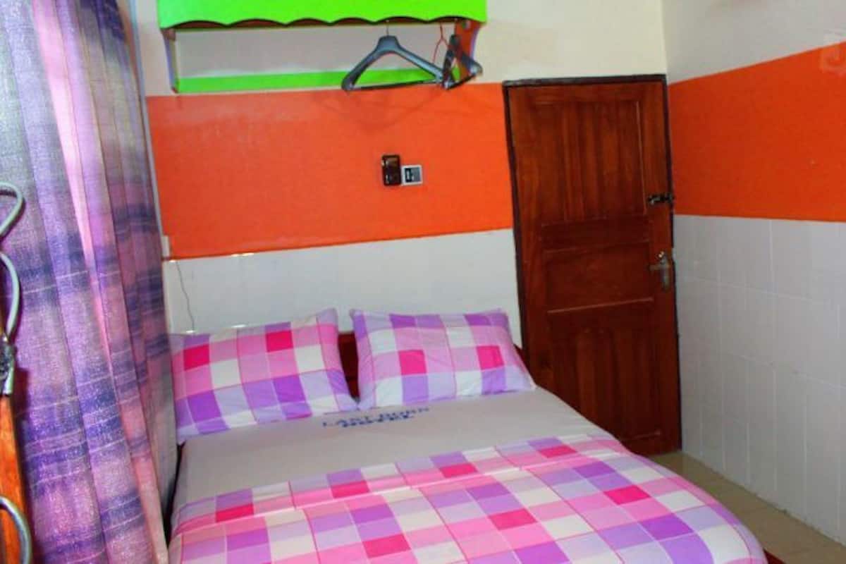 Un dormitorio con una cama, una puerta de madera y un estante con un objeto verde.