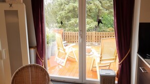 A room with a sliding glass door leading to an outdoor patio with wooden furniture and a wooden fence. - Gasthaus Düther Schleuse (Fresenburg)
