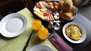 A breakfast setting with a plate of eggs, ham, cheese, and bread, along with two glasses of orange juice and a salt shaker. - Gasthaus Düther Schleuse (Fresenburg)