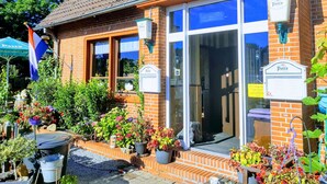 A brick building with large windows and a sign indicating it is a business. There are potted plants and flowers in front. - Gasthaus Düther Schleuse (Fresenburg)