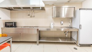 A modern kitchen with stainless steel appliances, a microwave, a kettle, and a sink.