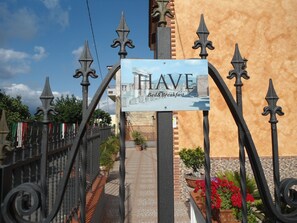 A sign with the text "HAVE Bed & Breakfast" in front of a building with a brick facade and a tiled pathway.