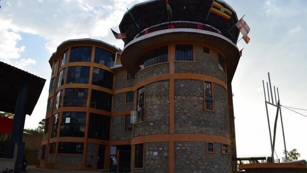 A multi-story building with a stone facade, multiple balconies, and flags.