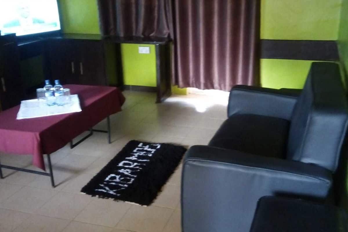 Una habitación con una mesa roja, un tapete negro con texto blanco, un televisor y un sofá.