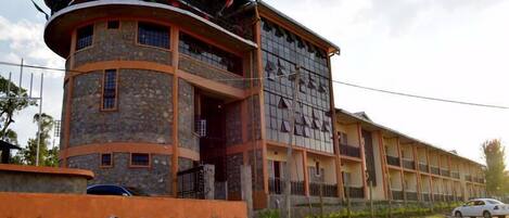 Un edificio con fachada de piedra curva, una sección con techo plano y varios ventanales.