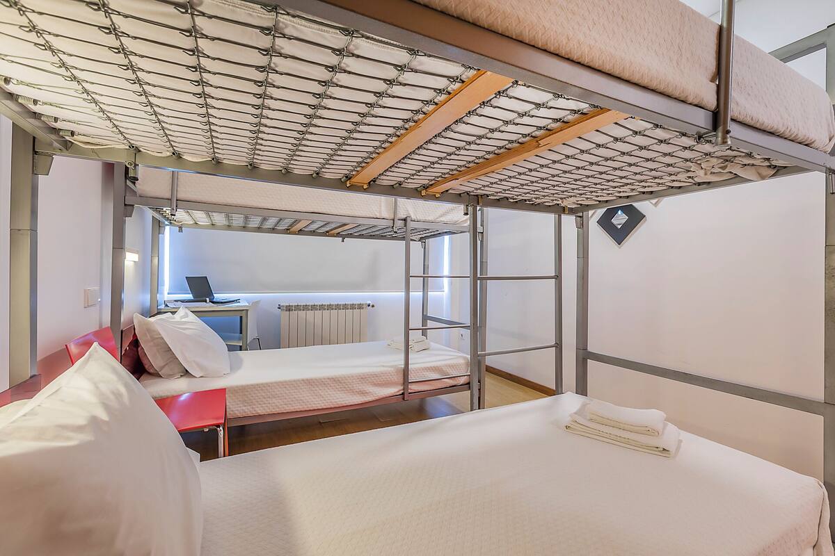 Quarto com beliche, escrivaninha e janela.