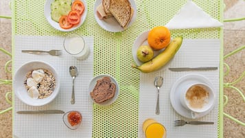 Una escena de desayuno con diversos alimentos y utensilios sobre un mantel verde.