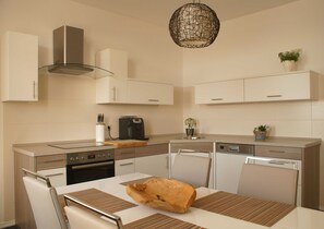 A modern kitchen with a built-in oven, a coffee maker, and a dining area with a table and chairs.