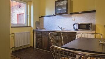 A compact kitchen with a microwave, a kettle, and a sink.