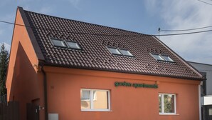 Un bâtiment avec un toit recouvert de tuiles brunes, deux fenêtres et une enseigne indiquant « appartements avec jardin ».