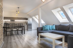 A modern loft apartment with a kitchen, dining area, and living room. - Garden apartments (Prešov)