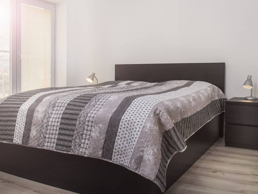 Un dormitorio moderno con una cama grande, un cabecero oscuro y dos lámparas de noche.