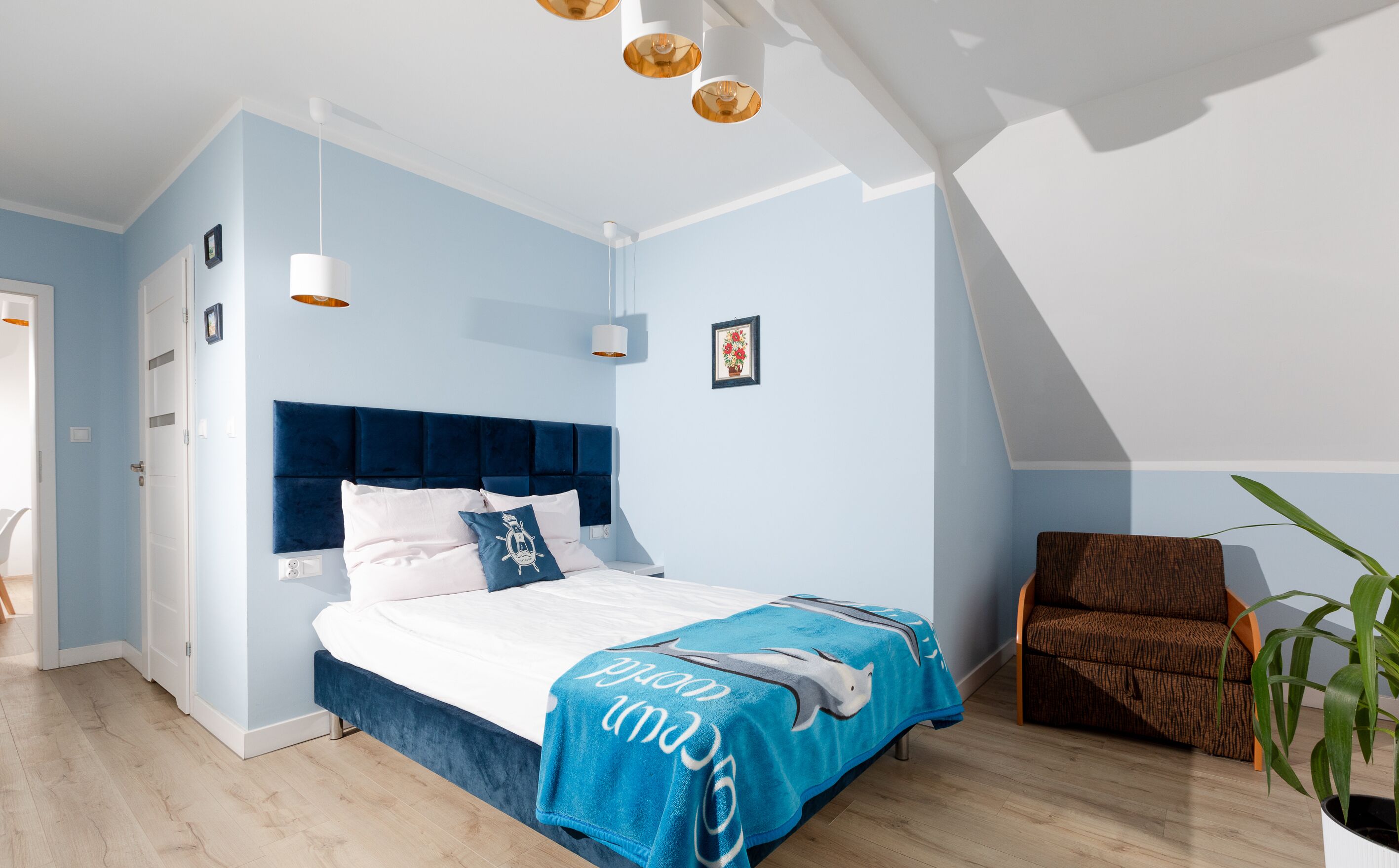 A modern bedroom with a bed, a chair, and a potted plant.