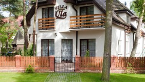 Un bâtiment à deux étages, sur lequel on peut lire l’inscription « Villa Una ». Il est doté d’un balcon avec des balustrades en bois, de grandes fenêtres et d’une entrée en briques.