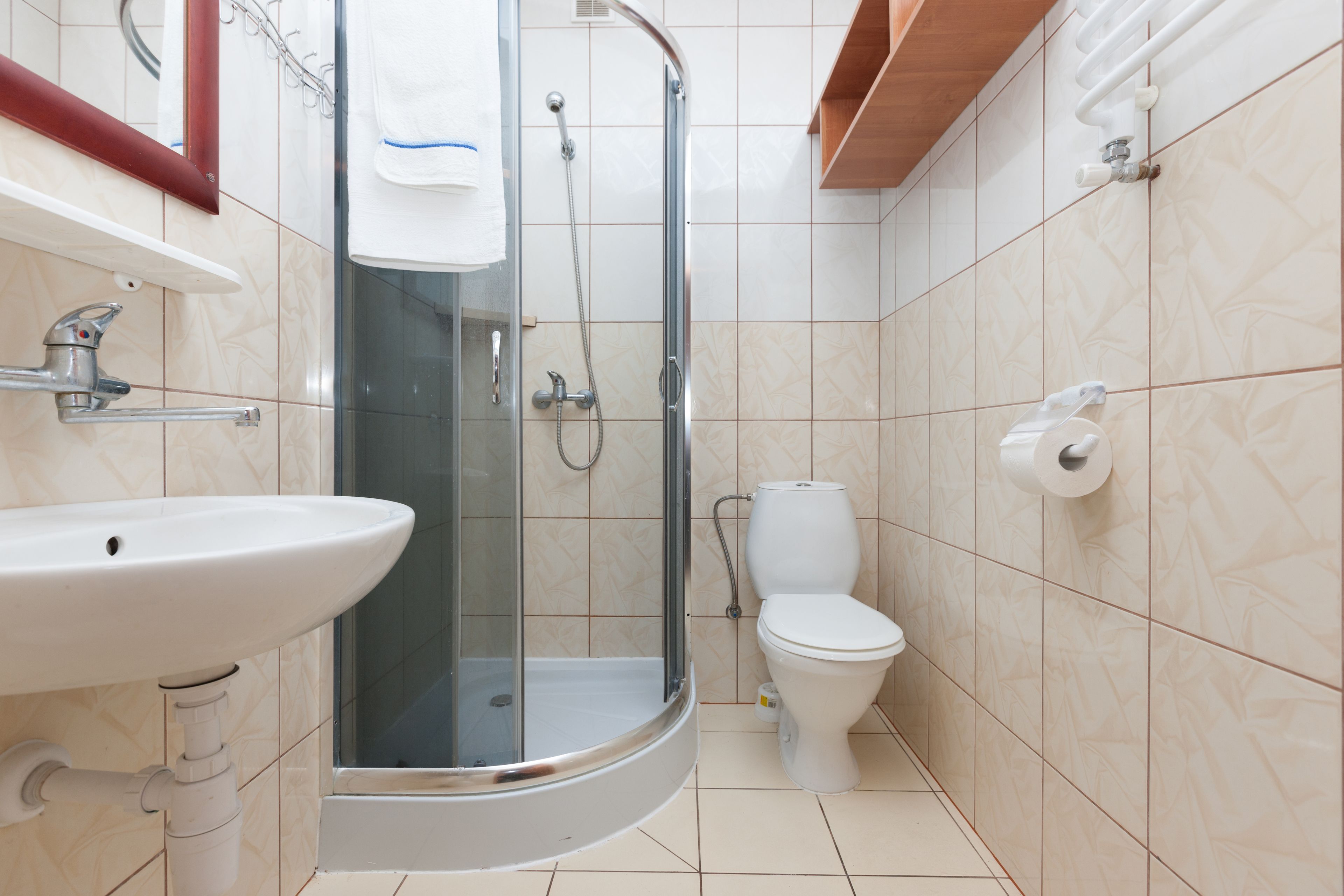 Ein Badezimmer mit einer Duschkabine, einem weißen Waschbecken und einer Toilette.
