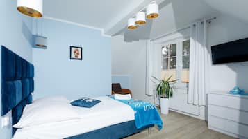 A bedroom with a bed, a chair, a potted plant, a TV, and a dresser.