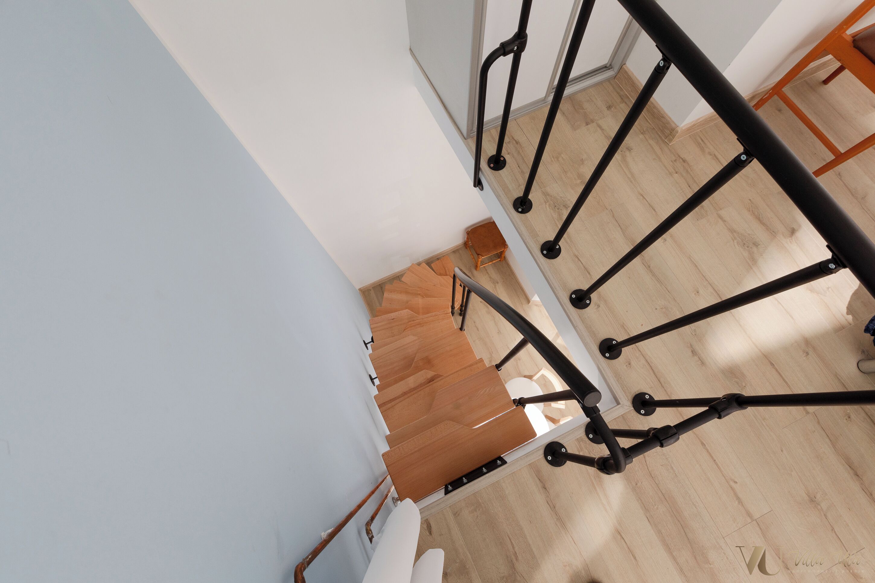 Una escalera con acabado de madera y barandales de metal negro.