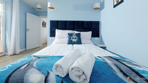 Une chambre à coucher avec un lit, des serviettes blanches, une tête de lit bleue et un tableau accroché au mur.