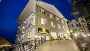 A multi-story hotel with a green and white facade, a prominent sign, and a staircase leading to the entrance. - Daizzo Maple Residency (Gangtok)