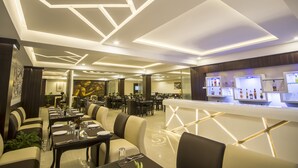 A modern restaurant with geometric ceiling designs, a bar area with illuminated shelves, and a dining area with booths and tables. - Daizzo Maple Residency (Gangtok)
