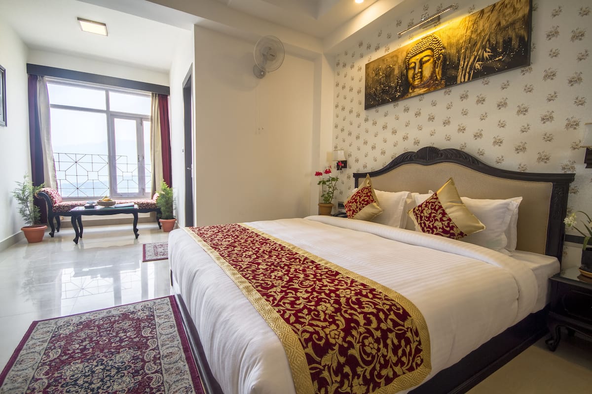 Un dormitorio espacioso con una cama grande, vistas al mar a través de una ventana y una pintura de Buda en la pared.