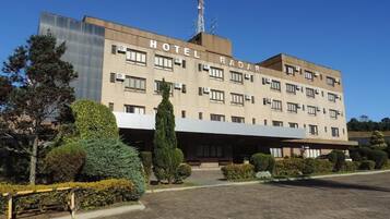 A multi-story hotel with a flat facade, air conditioning units, and a clear sky.