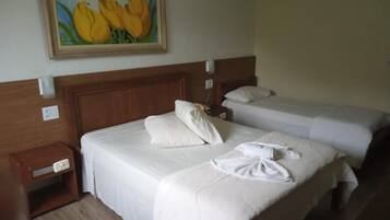 Habitación de hotel con dos camas, un cuadro de flores amarillas en la pared y una mesita de noche con una lámpara.