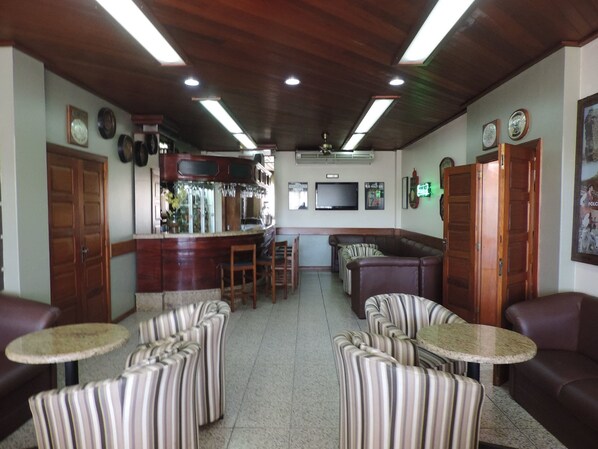 A bar area with a counter, seating, and a television.