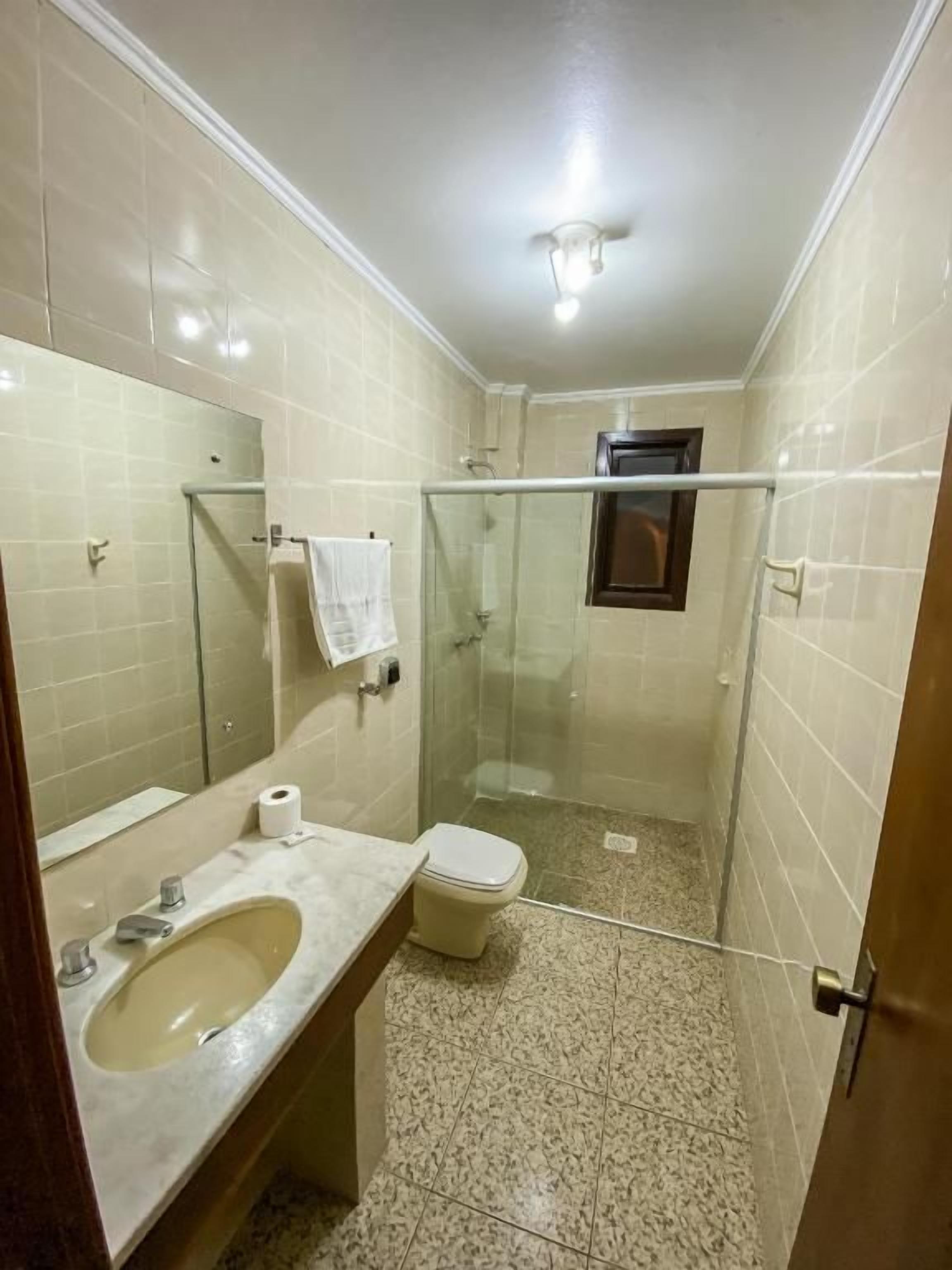 Ein Badezimmer mit Waschbecken, Toilette und Duschkabine aus Glas.