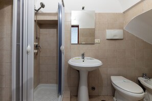 A bathroom with a shower, sink, toilet, and mirror. - Appartamento Il Barco (Ostuni)